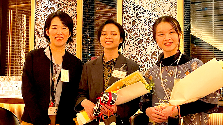 恩田サステナビリティ経営推進部長による卒業生（（左）マルシアさん、（右）エンジェルさん）への花束贈呈